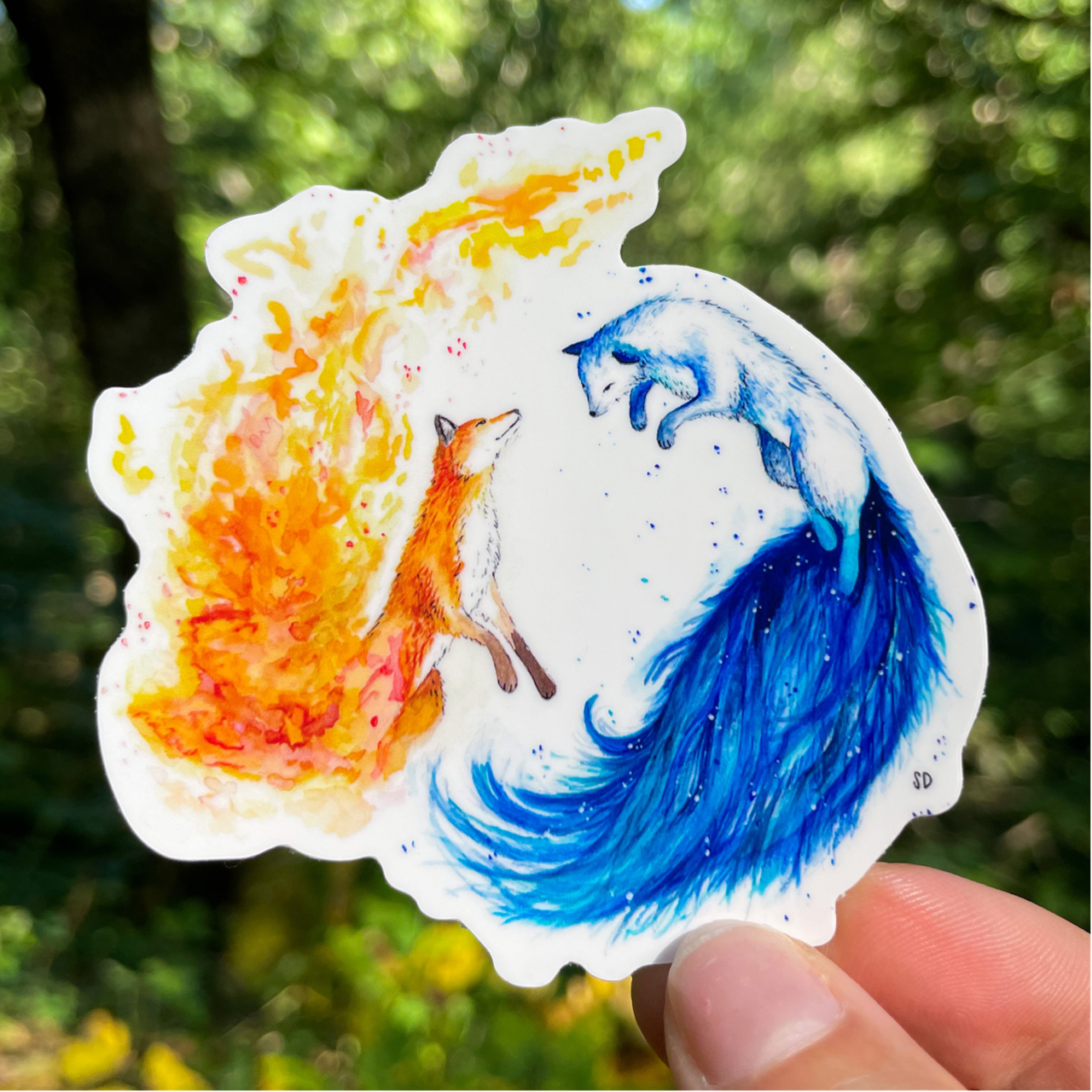 A close-up image of the waterproof, vinyl, dye-cut sticker depicting a watercolor painting from the Wild Planet Creations wild animal collection of fire and ice foxes.