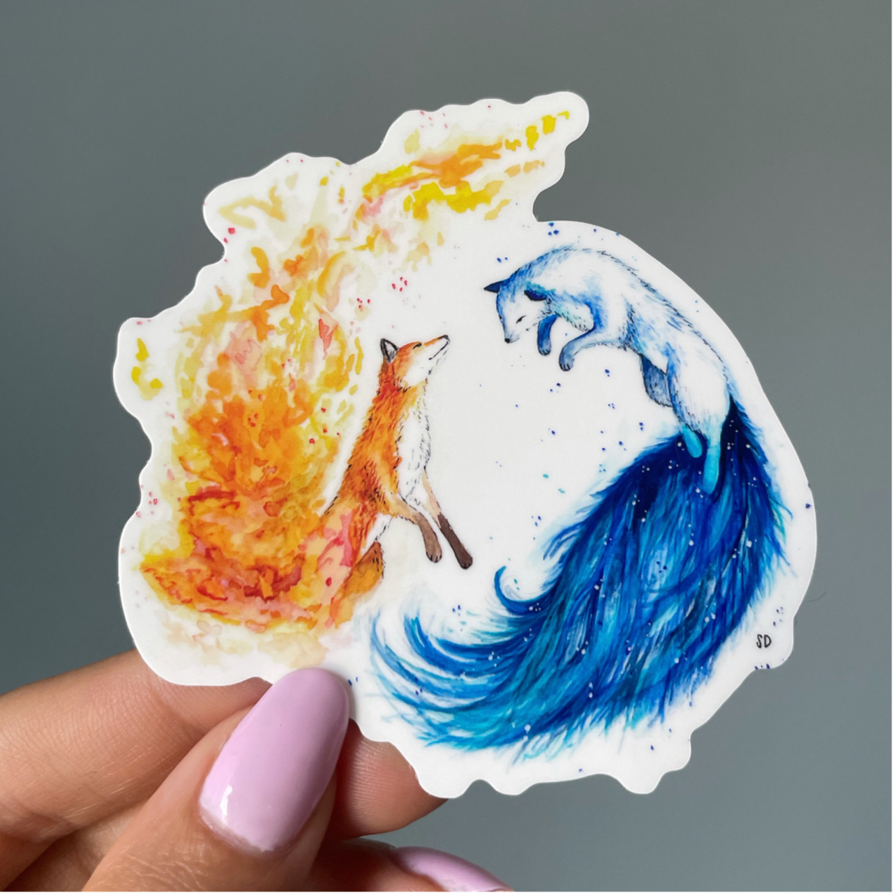 A close-up image of the waterproof, vinyl, dye-cut sticker depicting a watercolor painting from the Wild Planet Creations wild animal collection of fire and ice foxes.