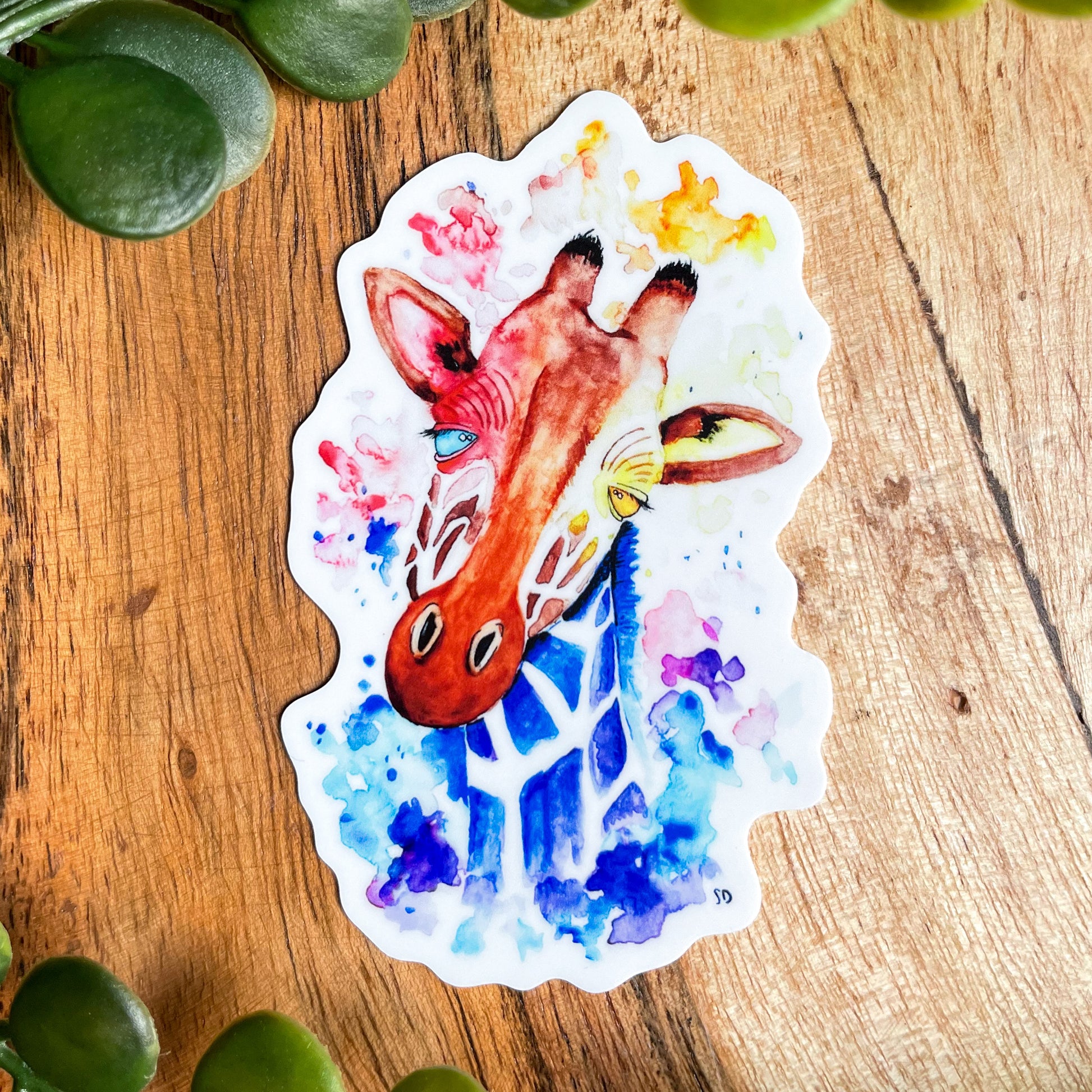 A close-up image of the waterproof, vinyl, dye-cut sticker depicting a watercolor painting from the Wild Planet Creations wild animal collection of a giraffe.