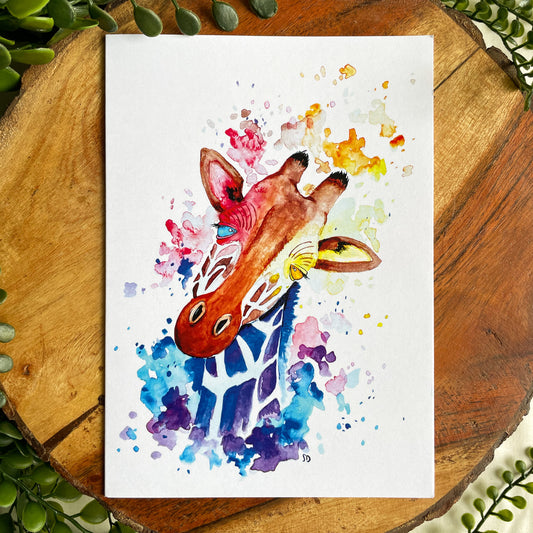 A 5x7" eco-friendly greeting card with original watercolor artwork from the Wild Planet Creations collection depicting a rainbow giraffe.