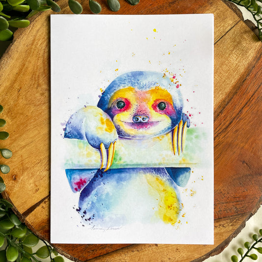 A 5x7" eco-friendly greeting card with original watercolor artwork from the Wild Planet Creations collection depicting a rainbow sloth.