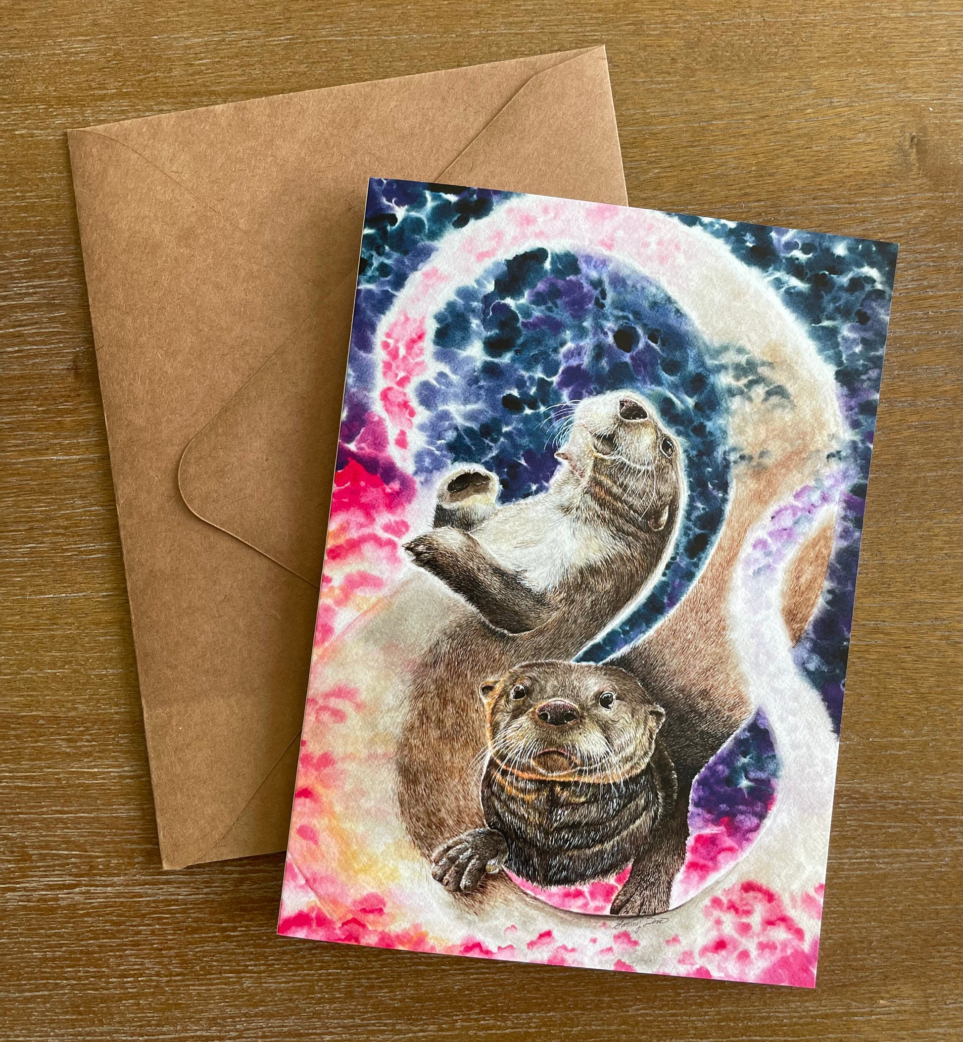 A 5x7" eco-friendly greeting card with original watercolor artwork from the Wild Planet Creations collection depicting two North American river otters.