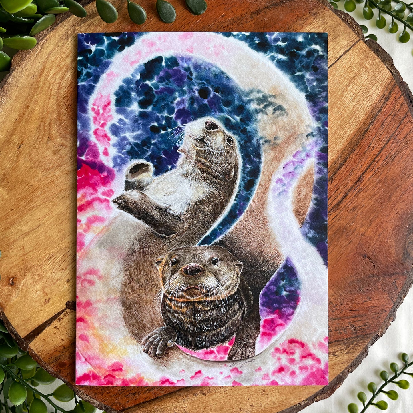 A 5x7" eco-friendly greeting card with original watercolor artwork from the Wild Planet Creations collection depicting two North American river otters.