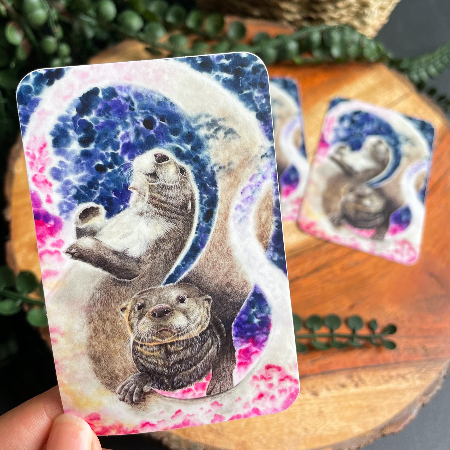 A close-up image of the waterproof, vinyl, dye-cut sticker depicting a watercolor painting from the Wild Planet Creations collection of two North American river otters