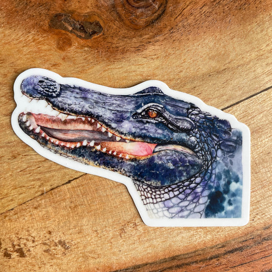 A close-up image of the waterproof, vinyl, dye-cut sticker depicting a watercolor painting from the Wild Planet Creations collection of an American alligator.